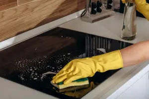 Kitchen,Cleaning,With,Rubber,Gloves,Spraying,Cleaner,On,Glass,Induction shutterstock 2760321581